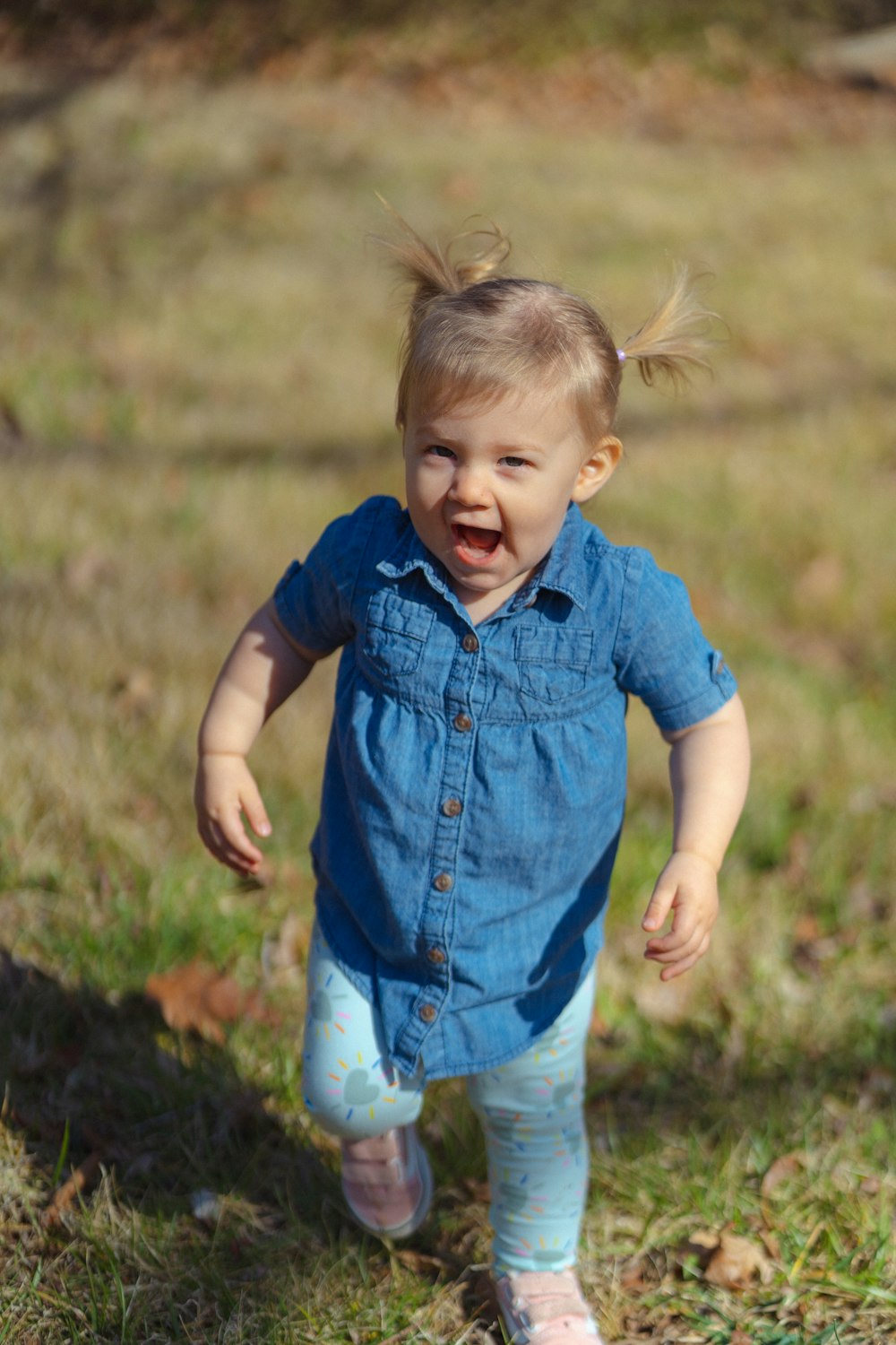 a little girl in a blue shirt is walking in the grass