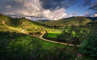 a lush green valley surrounded by mountains under a cloudy sky