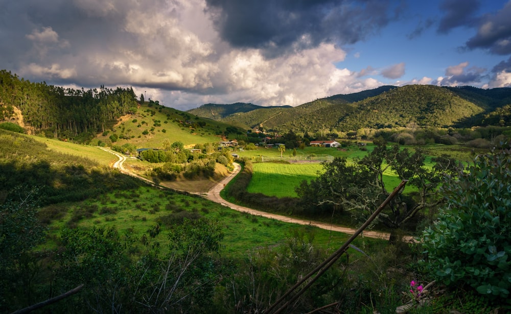 a lush green valley surrounded by mountains under a cloudy sky