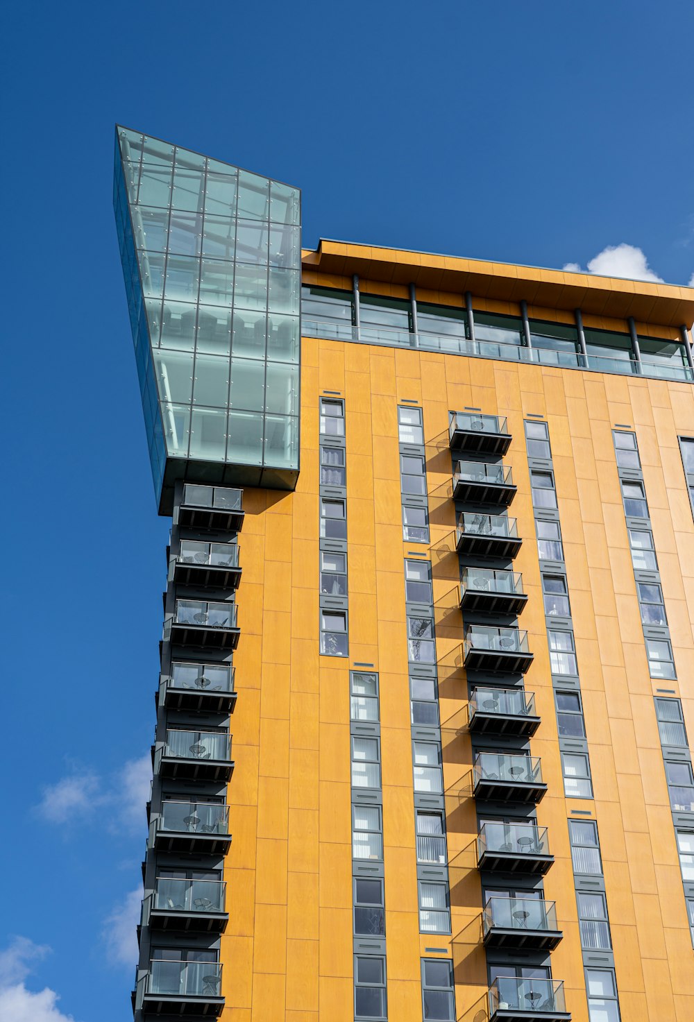 a tall yellow building with balconies against a blue sky