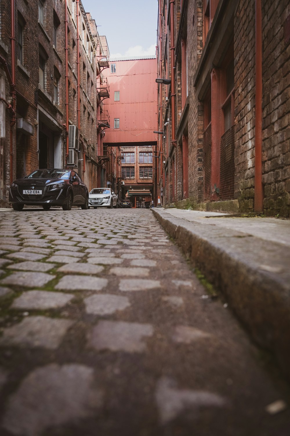 a narrow street with cars parked on both sides