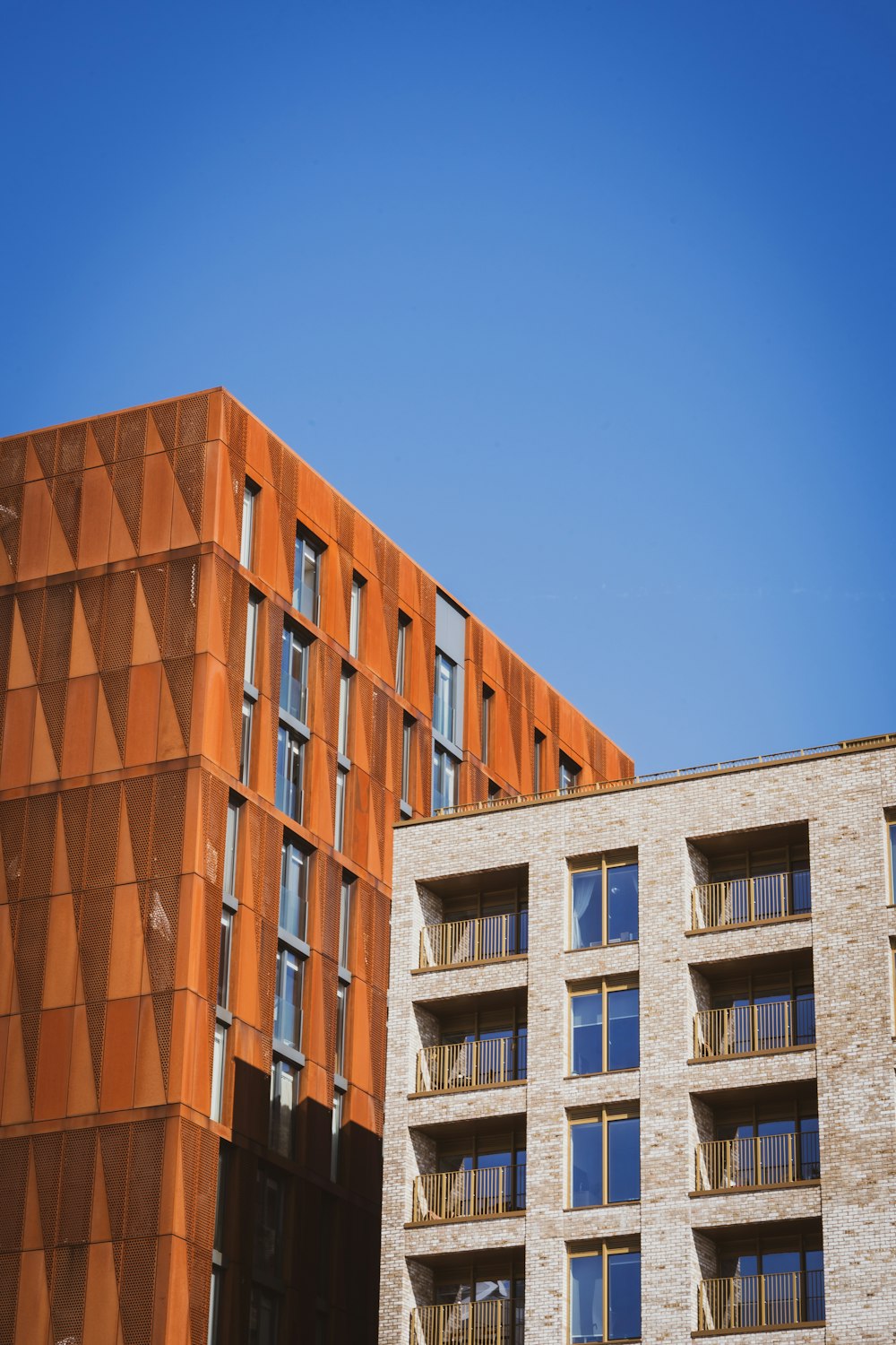 높은 벽돌 건물 옆에 있는 높은 주황색 건물