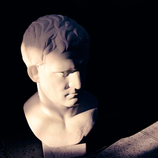 Bust of a famous Greek philosopher illuminated softly to highlight facial features and expression.