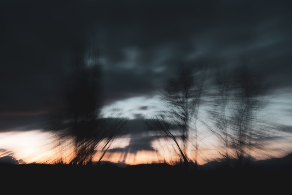 a blurry photo of a sunset with trees in the foreground