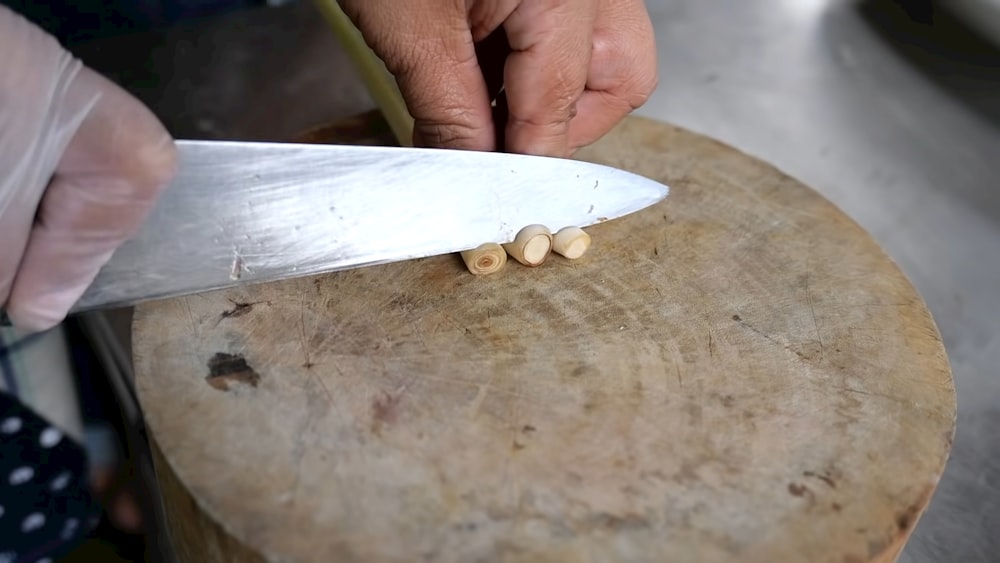 a person with a knife cutting something on a wooden board
