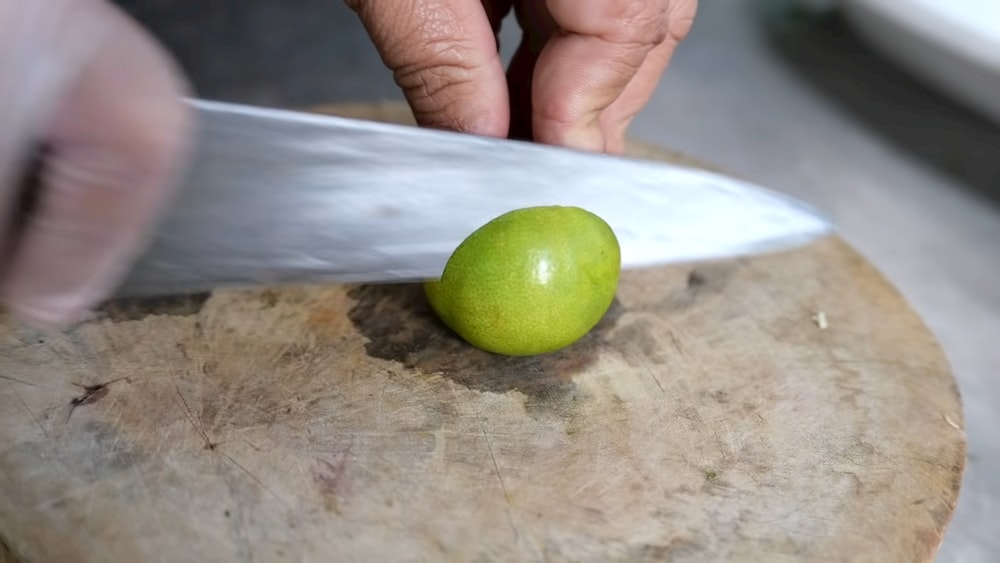 a person cutting a green apple with a knife