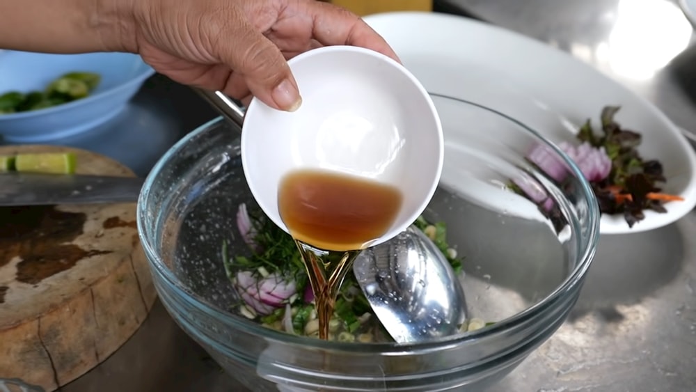a person pouring a liquid into a bowl of food