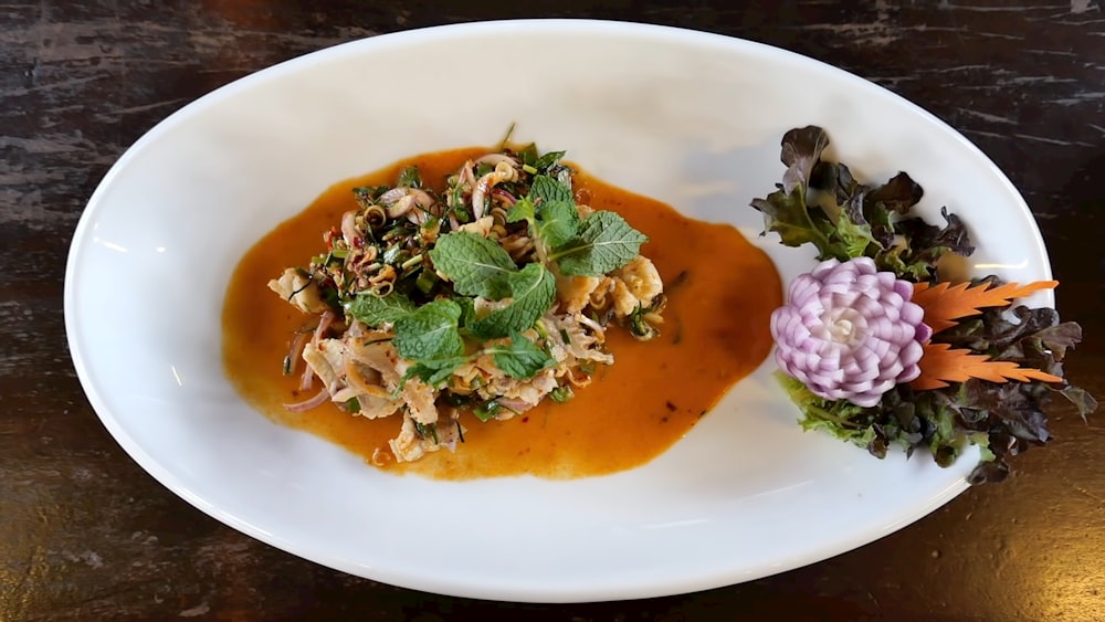 a white plate topped with a salad covered in sauce