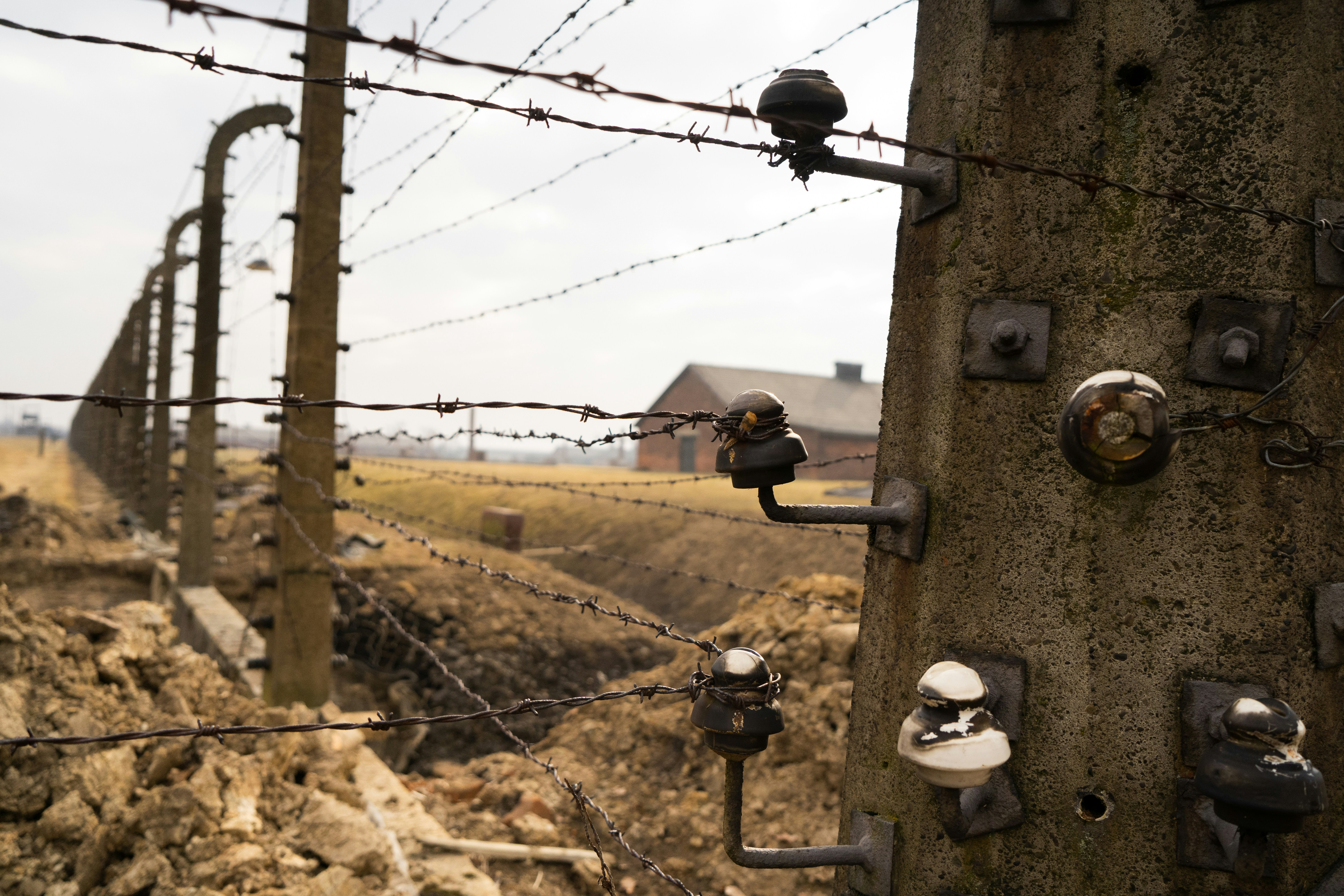 a barbed wire fence with a house in the background