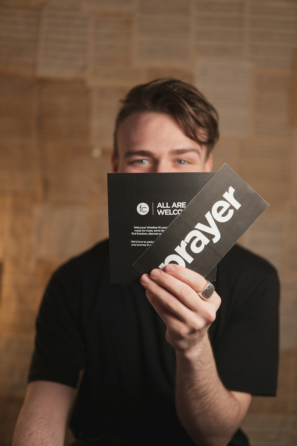 a man holding up a piece of paper with the word prayer printed on it