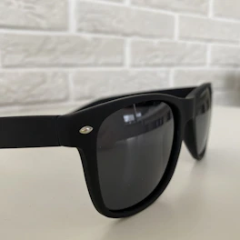 Close-up of sleek black sunglasses with subtle gold accents resting on a dark textured surface