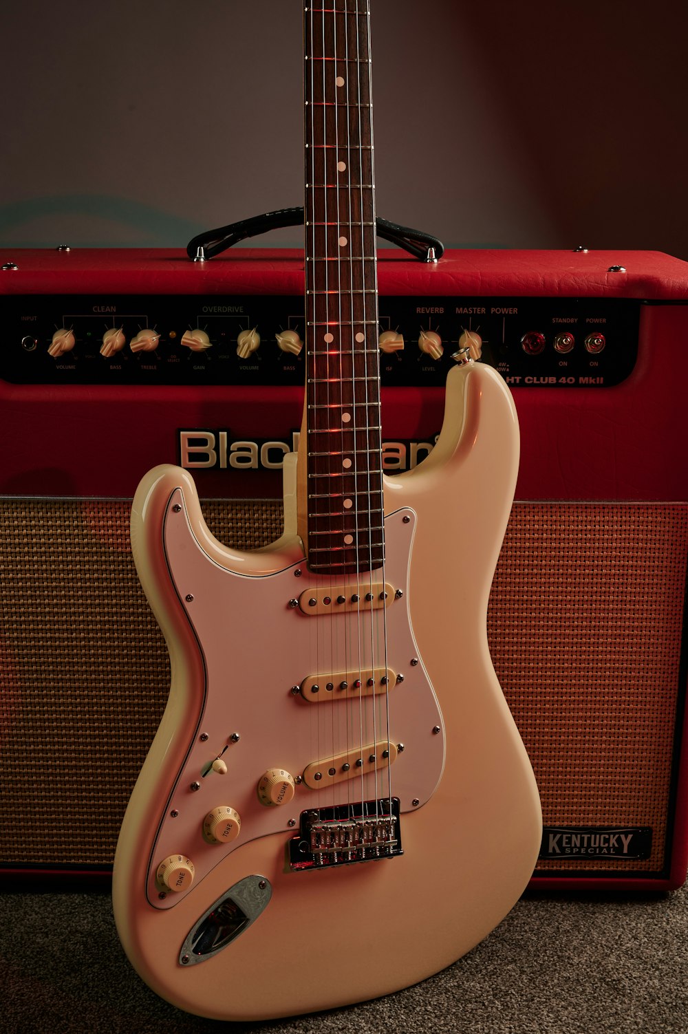 a pink guitar sitting next to a red amp