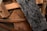 A collection of wooden planks and plywood pieces, arranged in a haphazard manner. The textures of the wood vary, with one prominently featuring dark, intricate patterns typical of oriented strand board. The colors range from light brown to dark brown, with some areas appearing worn and rough.