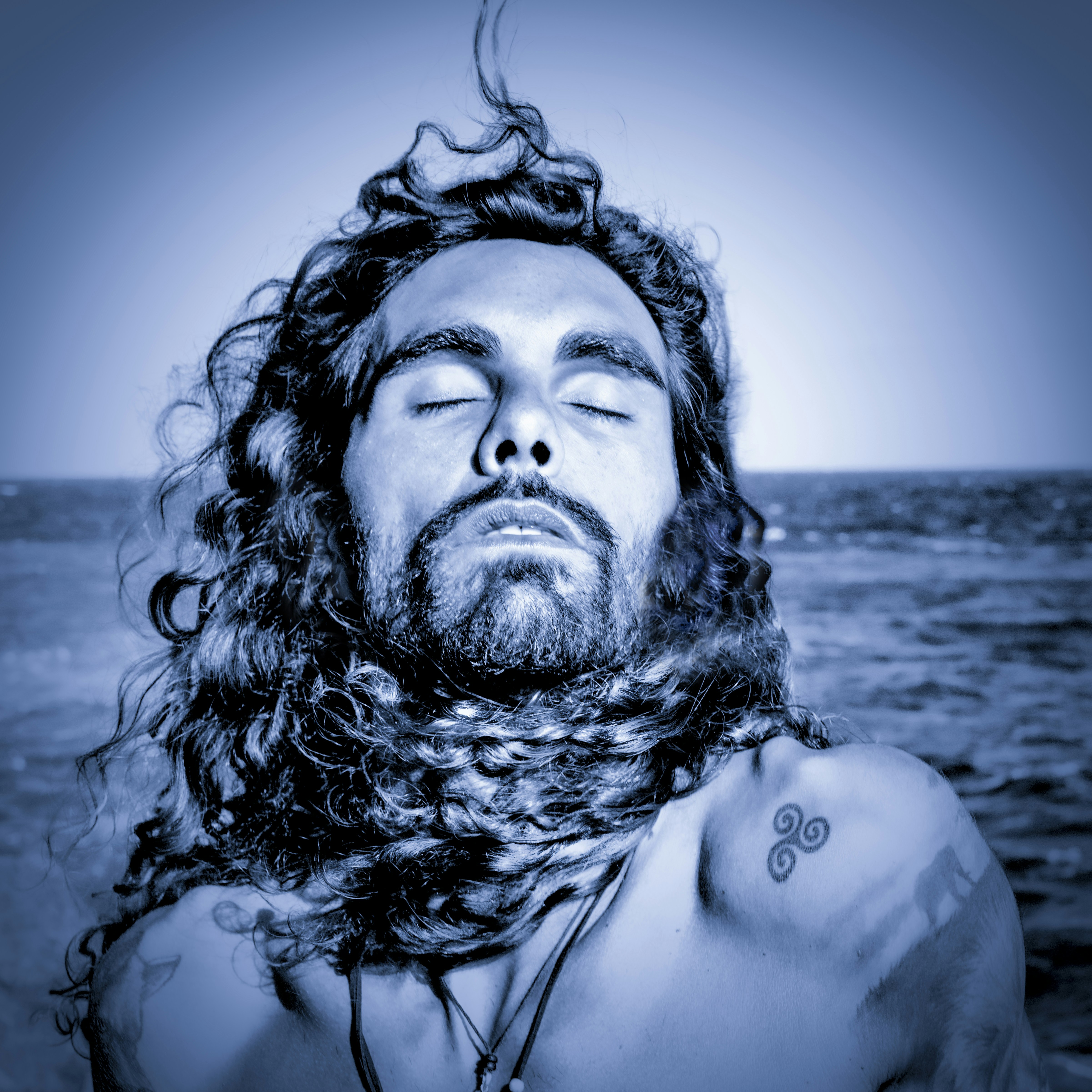 Foto zum Thema Ein Mann mit langen Haaren und einem Tattoo auf der