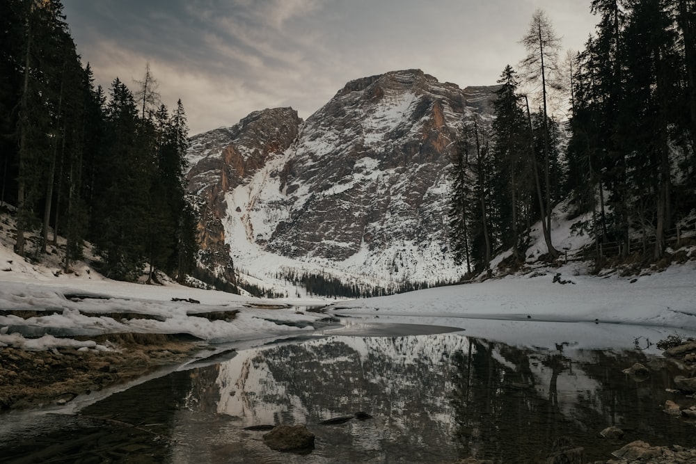 a snow covered mountain with a lake in the foreground