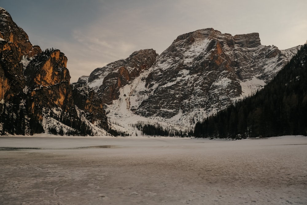 a snow covered mountain range with a lake in the foreground