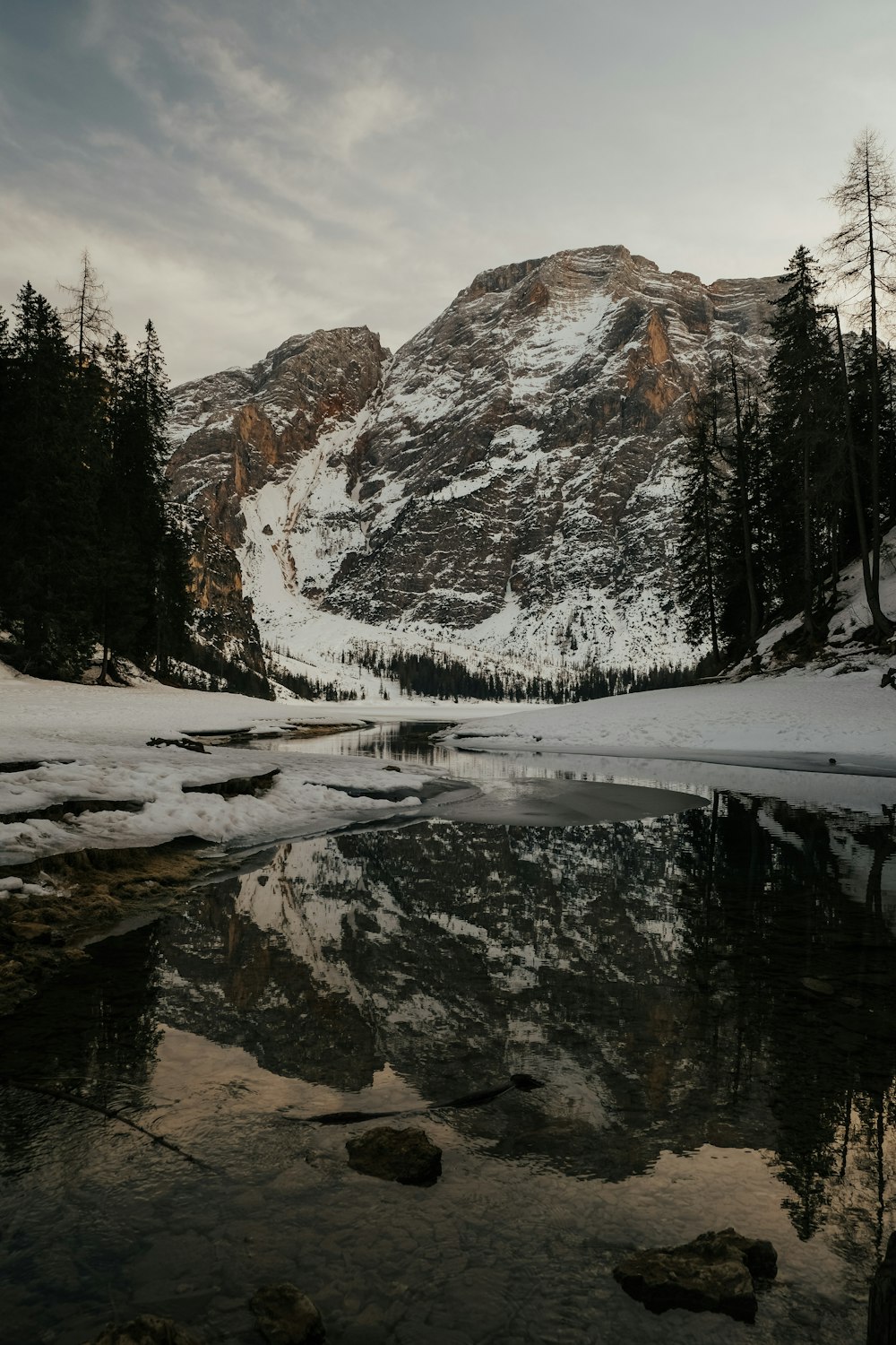 a snow covered mountain with a lake in the foreground