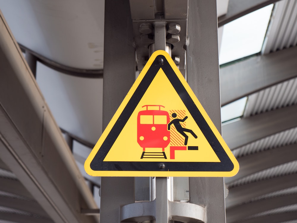 a yellow and black warning sign on a pole