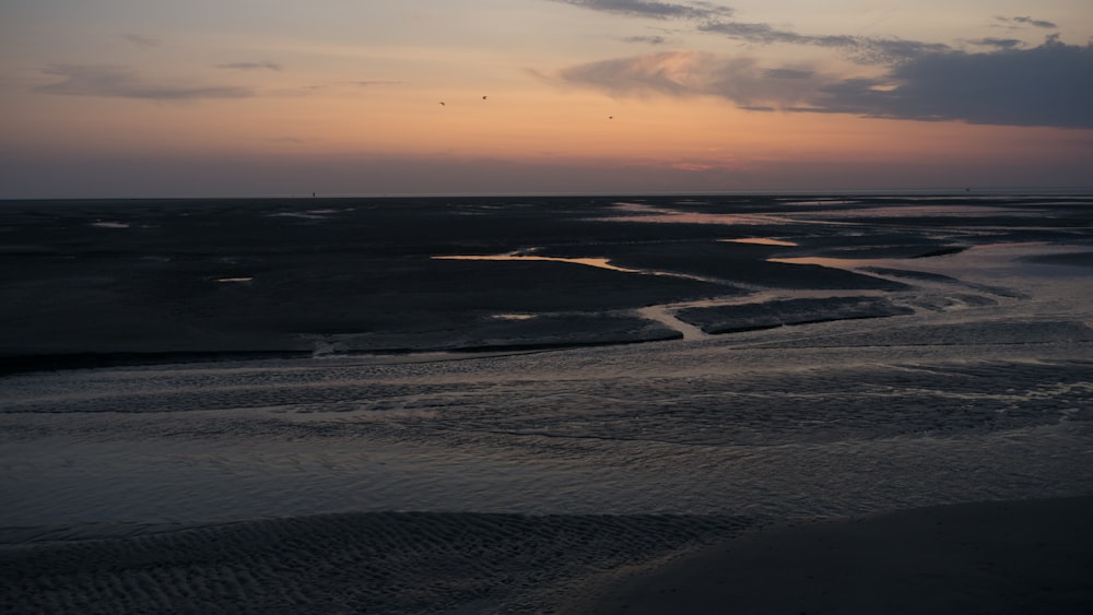 the sun is setting over the water at the beach