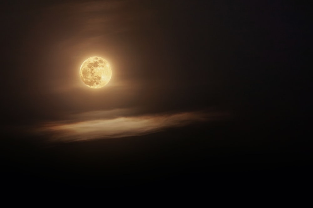 a full moon seen through the clouds in the night sky