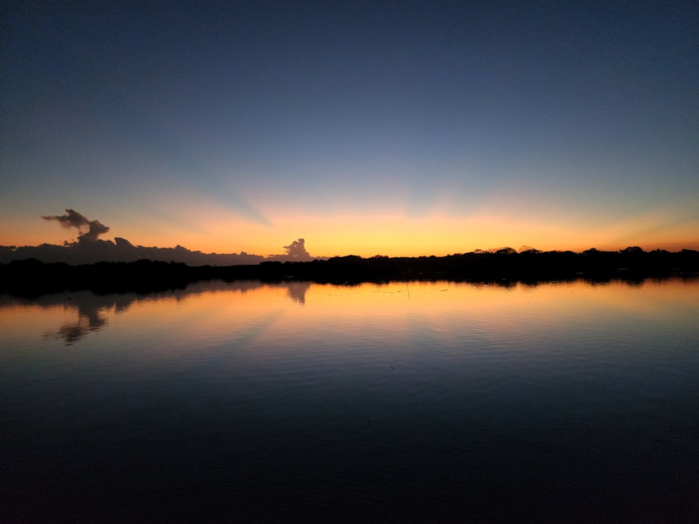 o sol está se pondo sobre um lago calmo