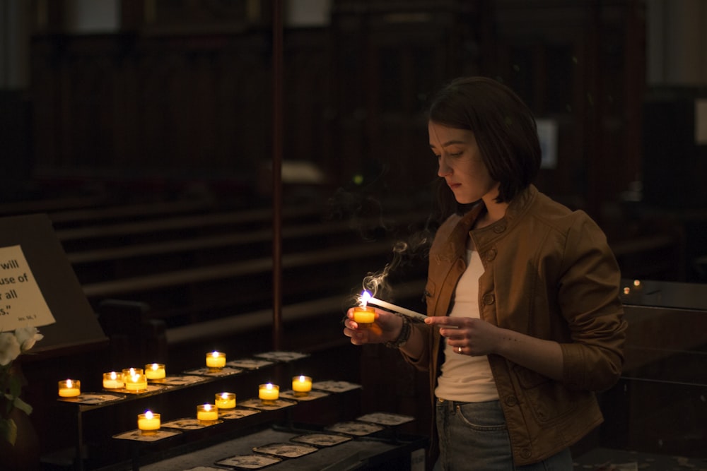 a woman lighting a candle in a church