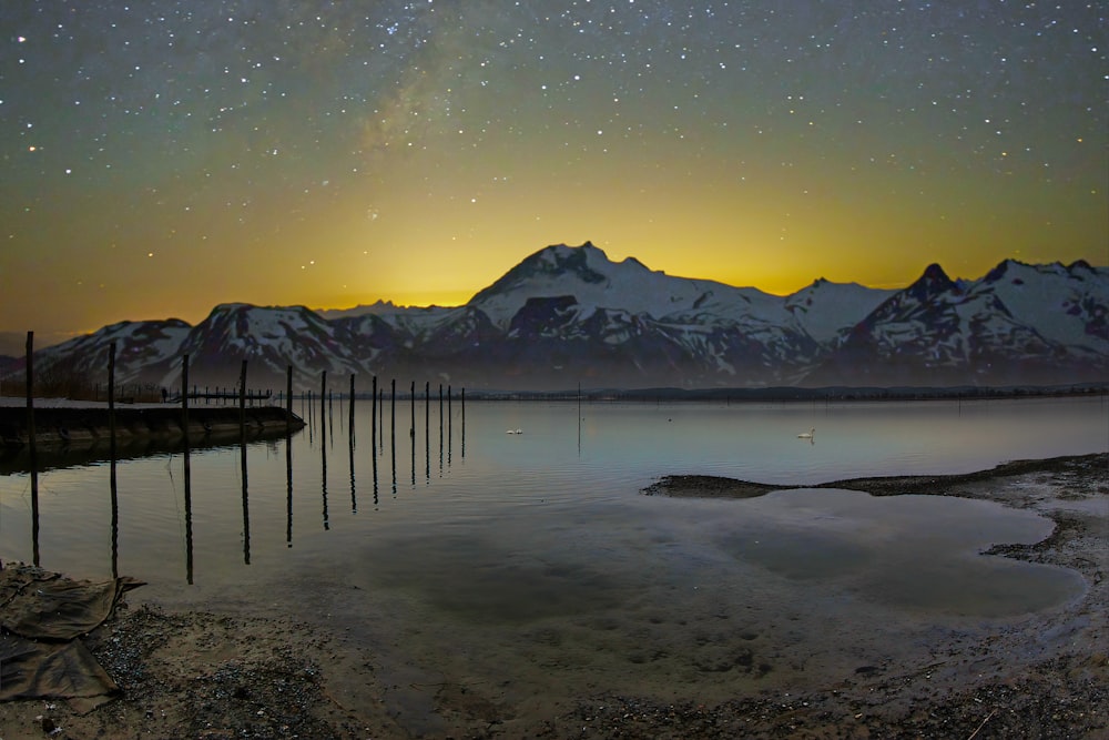 a body of water surrounded by mountains under a night sky