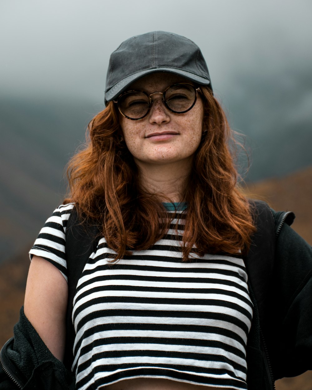 a woman with red hair wearing a hat and glasses