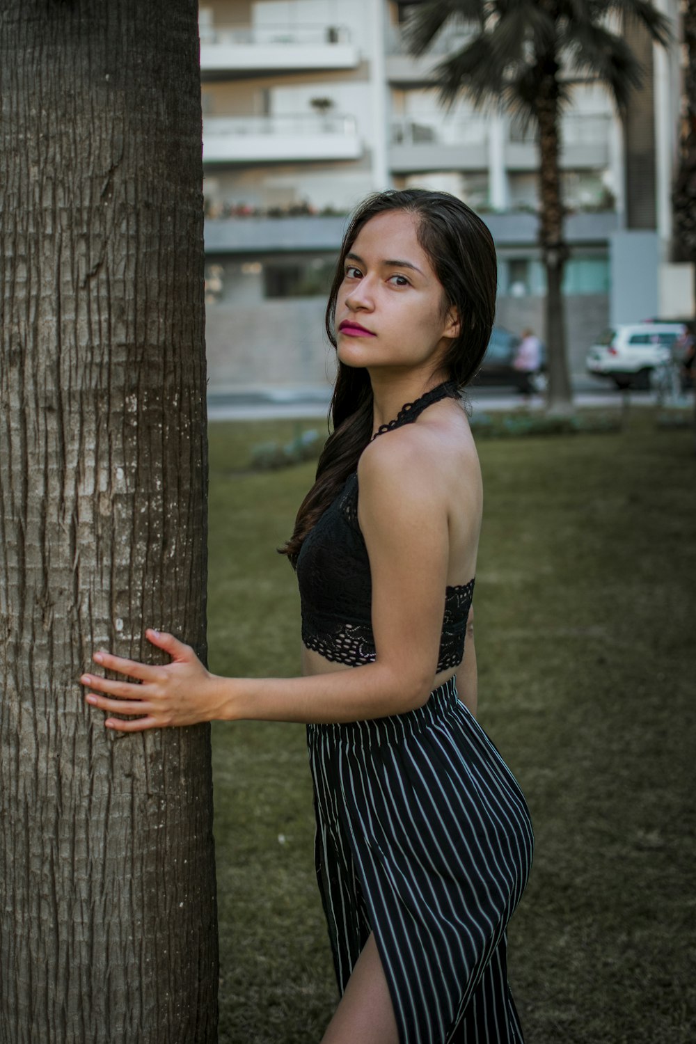 a woman leaning against a tree in a park