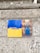 Two images are displayed on a stone wall. The first image on the left has a blue and yellow background with the text 'PRAY FOR UKRAINE'. The second image on the right is a religious icon depicting a haloed figure with hands raised.
