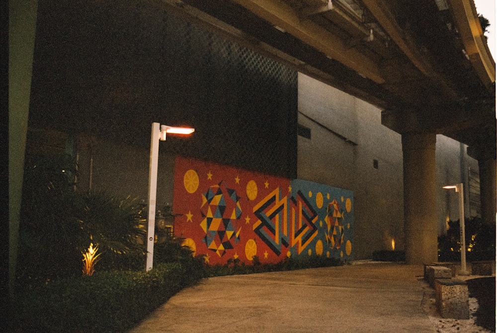 a mural on the side of a building under a bridge