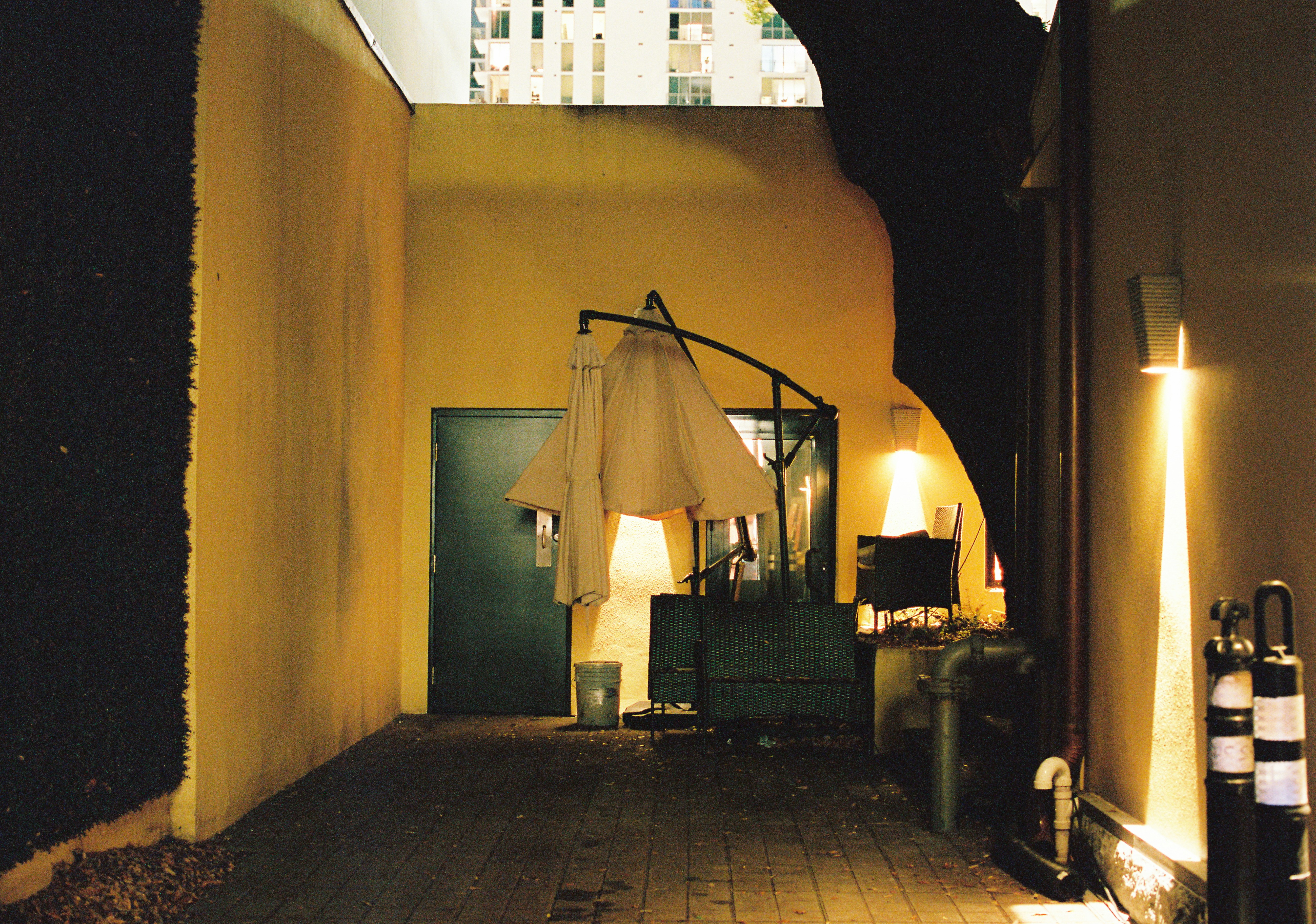 an alley way with an umbrella and some bottles of wine