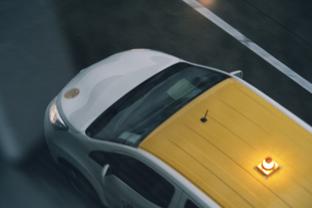 a yellow and white sports car driving down a street