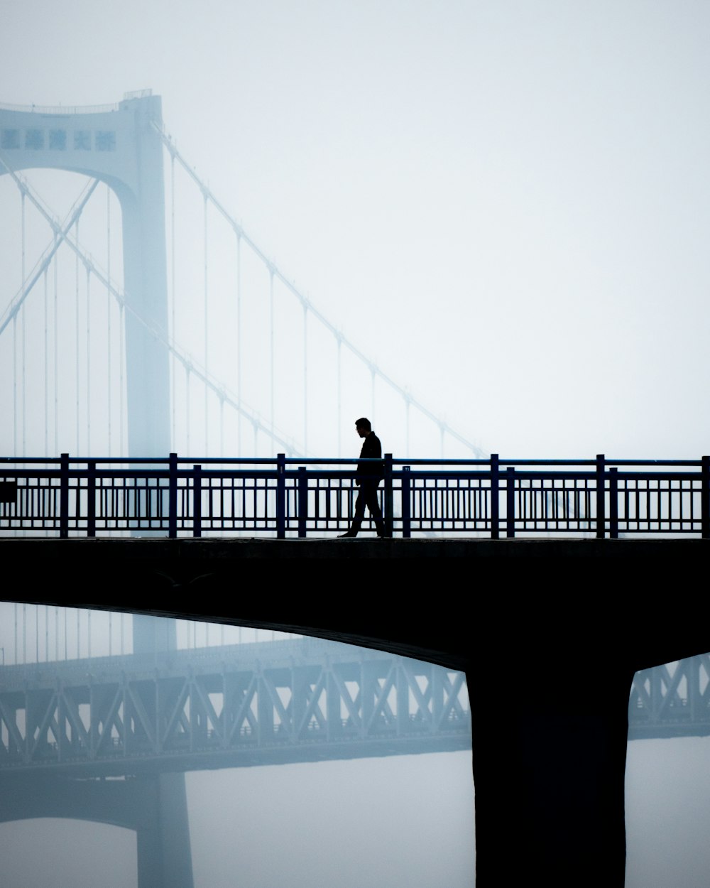 a man walking across a bridge in the fog