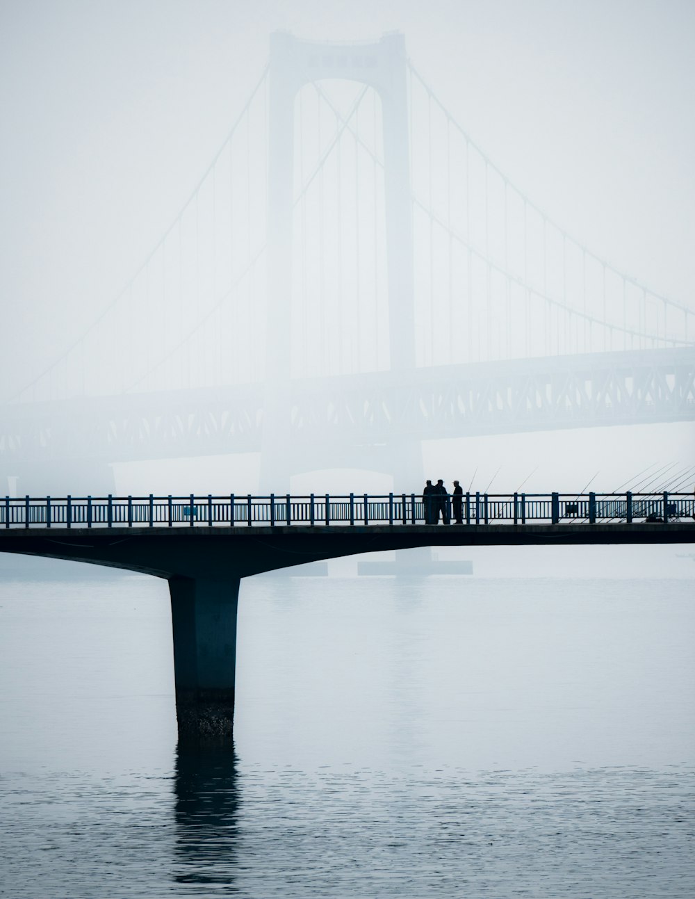 two people standing on a bridge over a body of water