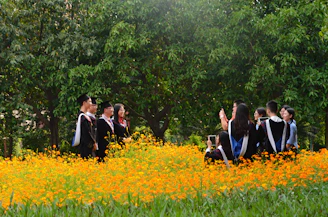 a group of people walking through a field of flowers
