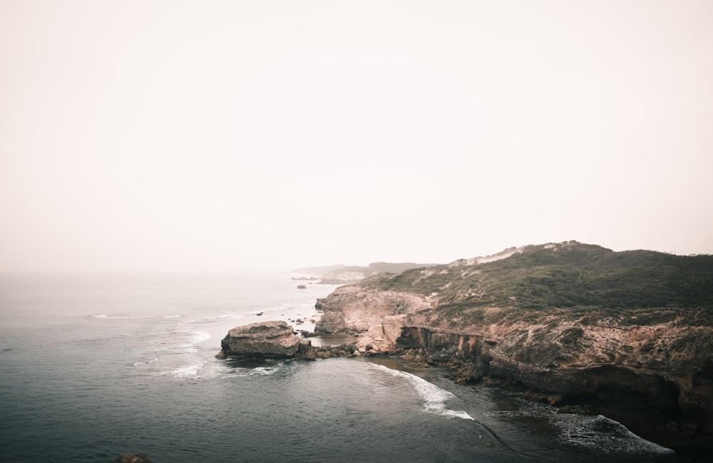 a large body of water next to a rocky cliff