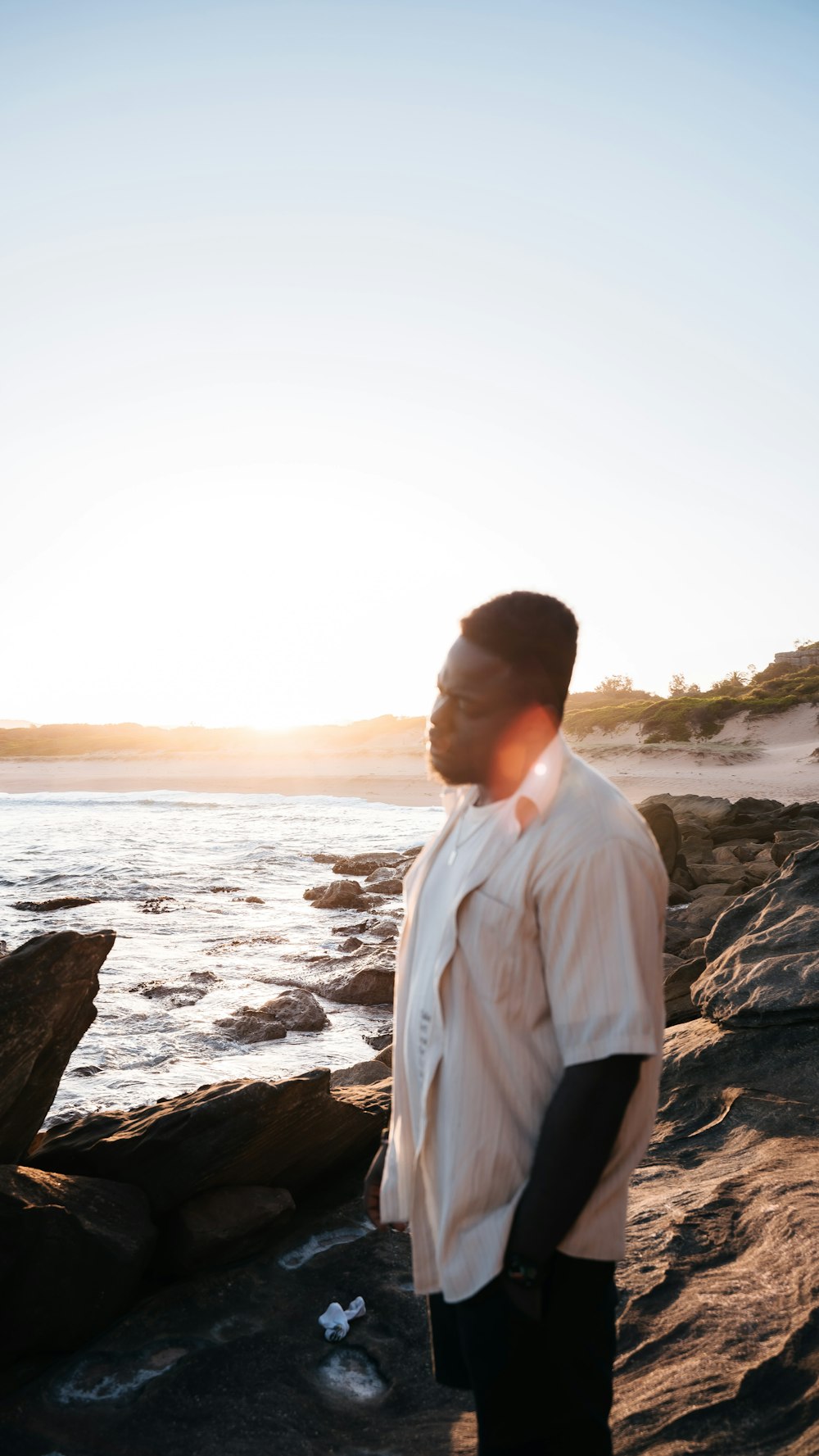 a man standing on top of a rocky beach next to the ocean