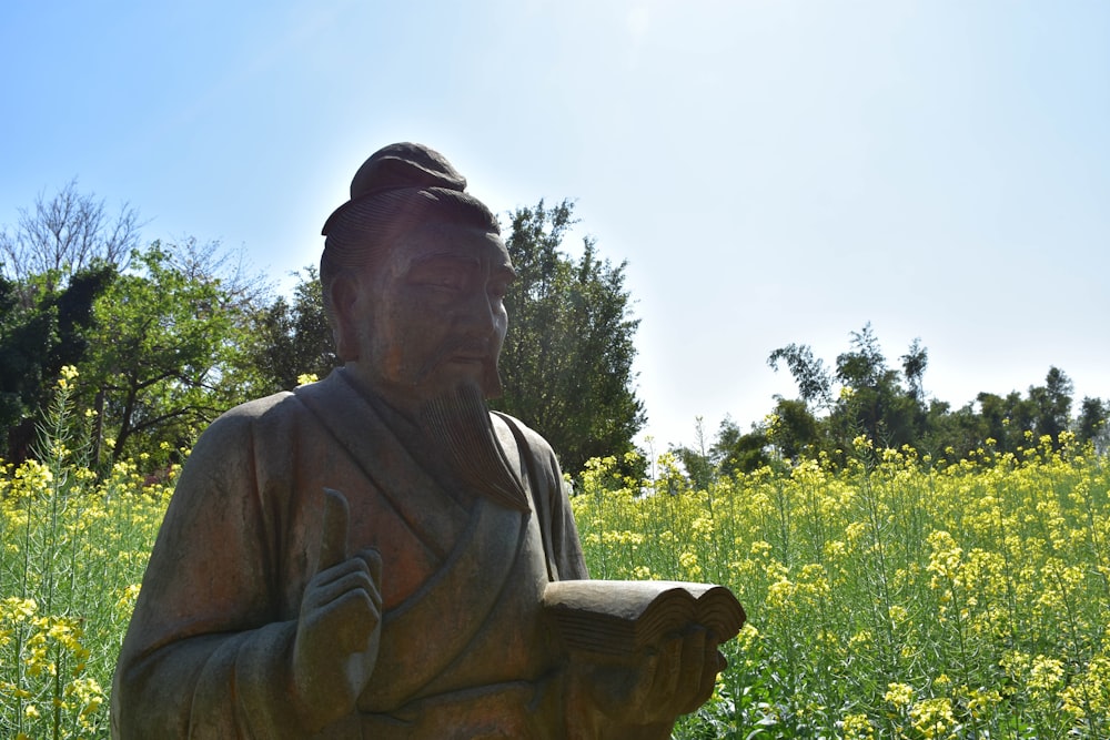 a statue of a person in a field of flowers