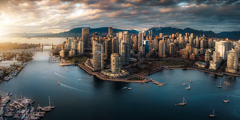 The Vancouver skyline against the mountains at dusk, seen across the water