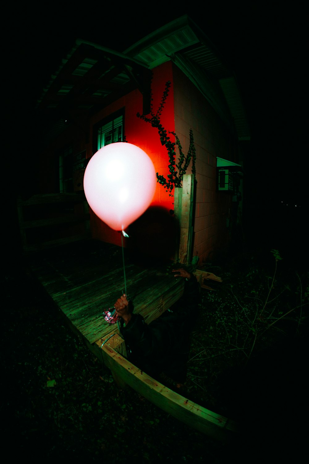 a person sitting on a porch holding a balloon