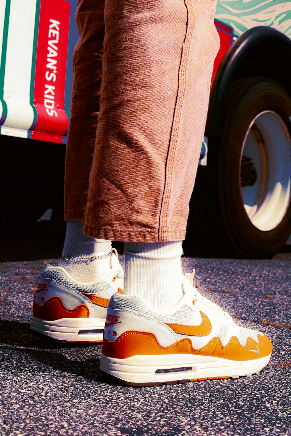 a person wearing orange and white shoes standing in front of a bus
