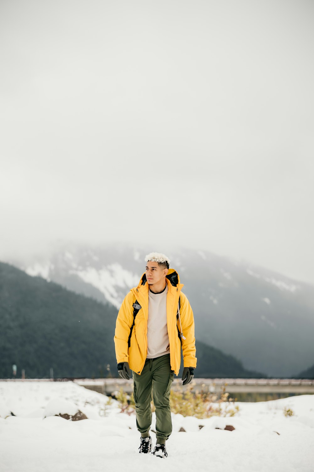 a man in a yellow jacket walking in the snow