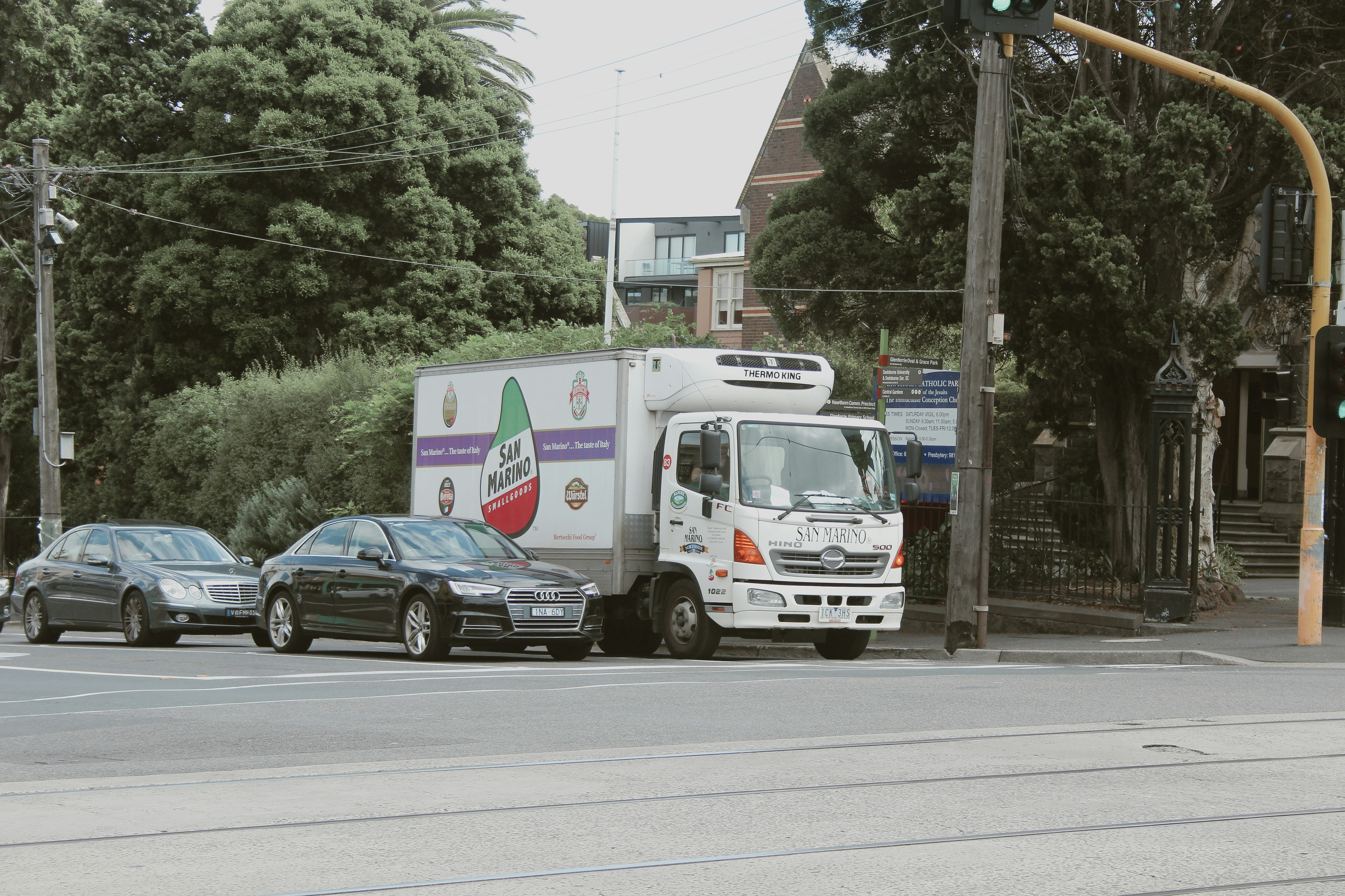 a delivery truck driving down a street next to parked cars