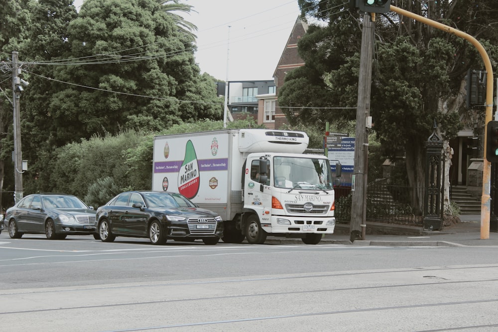 a delivery truck driving down a street next to parked cars