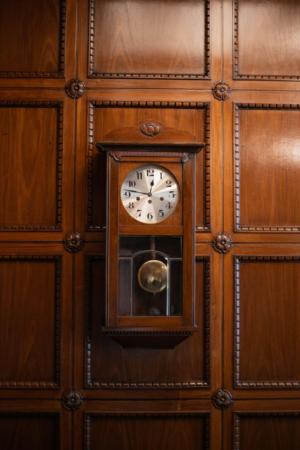 a clock mounted to the side of a wooden wall