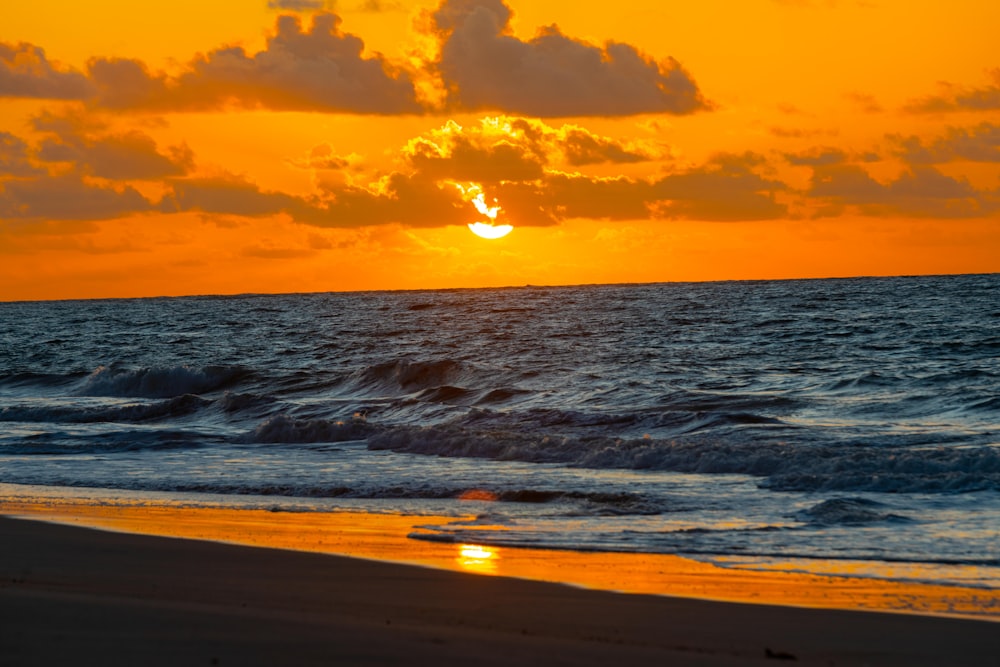 the sun is setting over the ocean on the beach