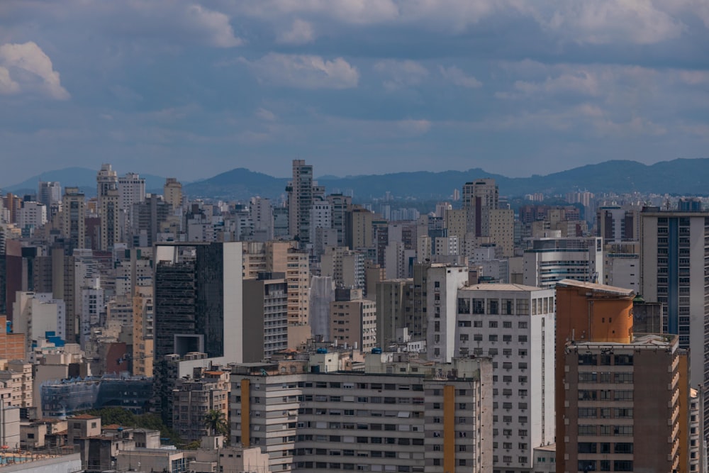 a city skyline with tall buildings and mountains in the background