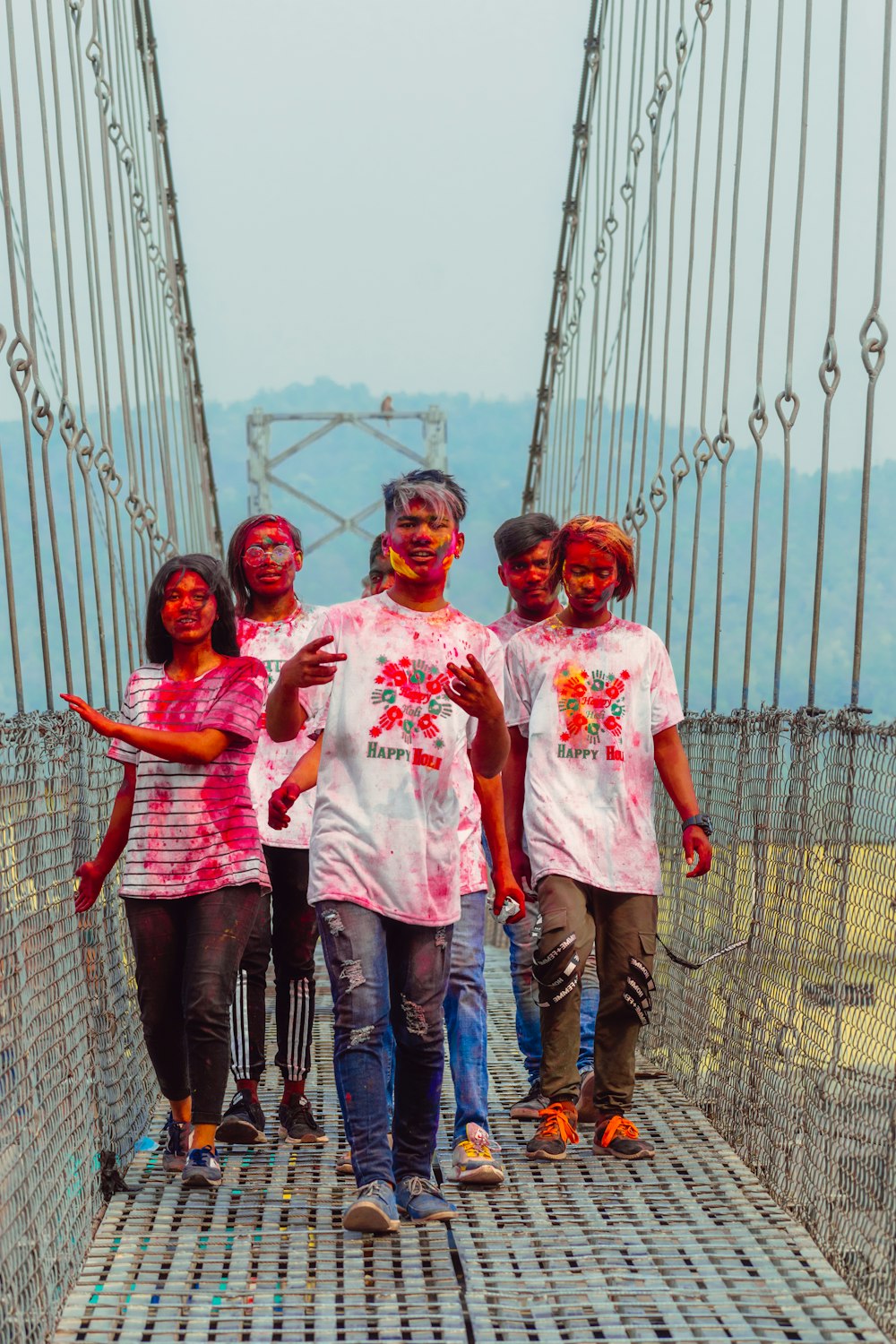 a group of people walking across a suspension bridge