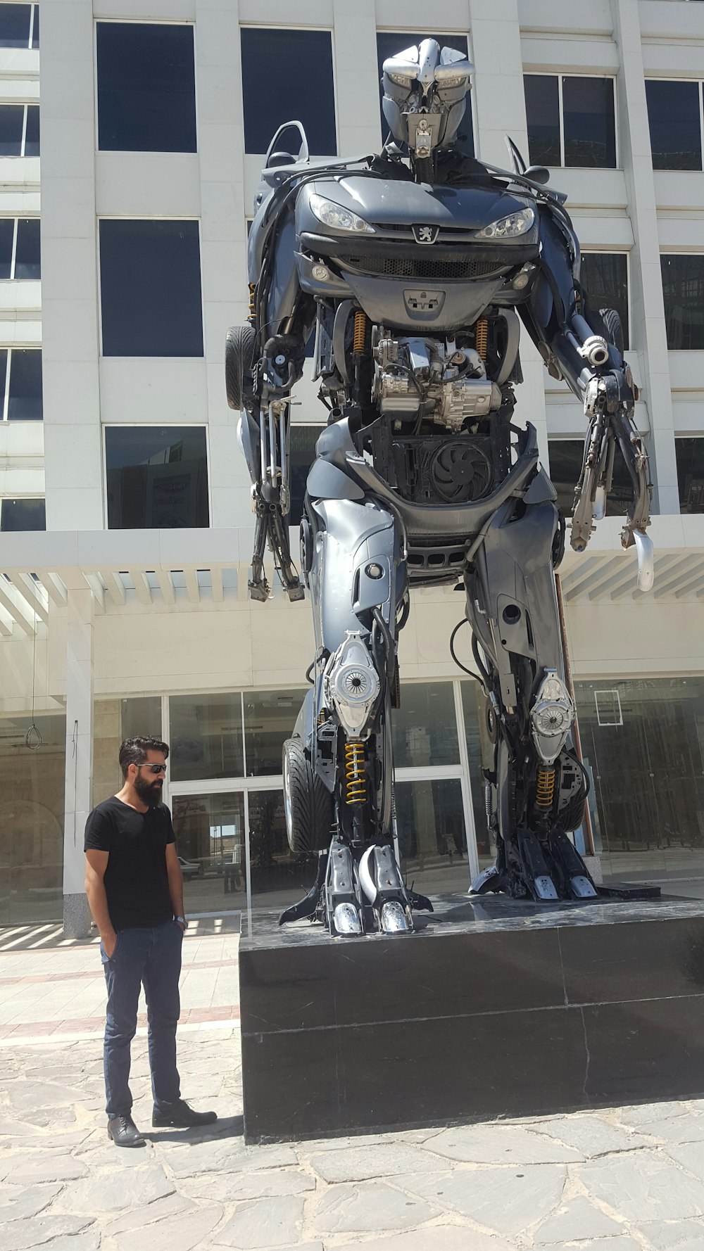 Un hombre de pie junto a una estatua de robot gigante